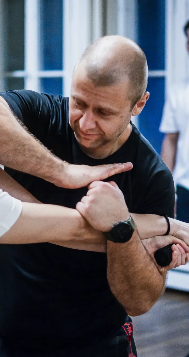 Hochkantbild von einem Trainer, der gerade einen Stockangriff abwehrt